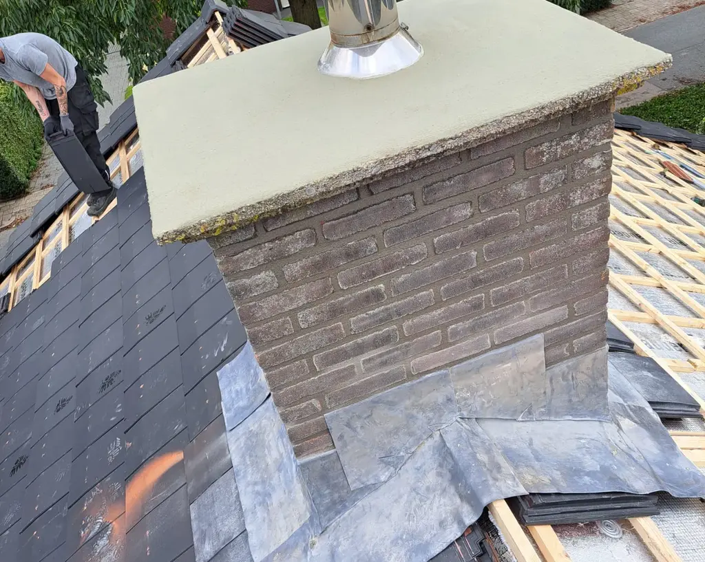 Gemetselde schoorsteen met nieuw voegwerk en loodslabben op een pannendak